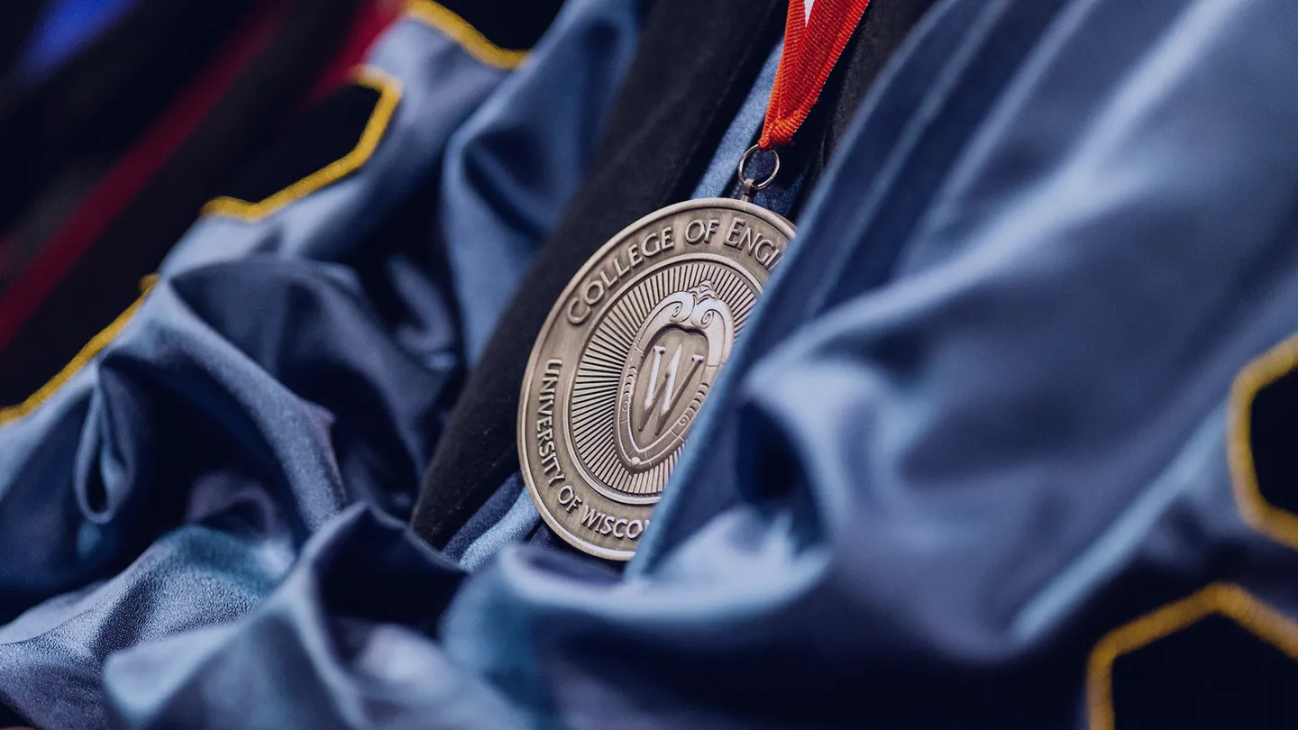 Closeup image of UW–Madison College of Engineering medallion laying against a blue academic robe