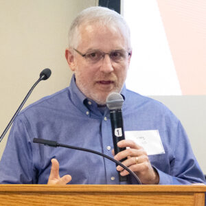 Greg Johll speaks into a microphone