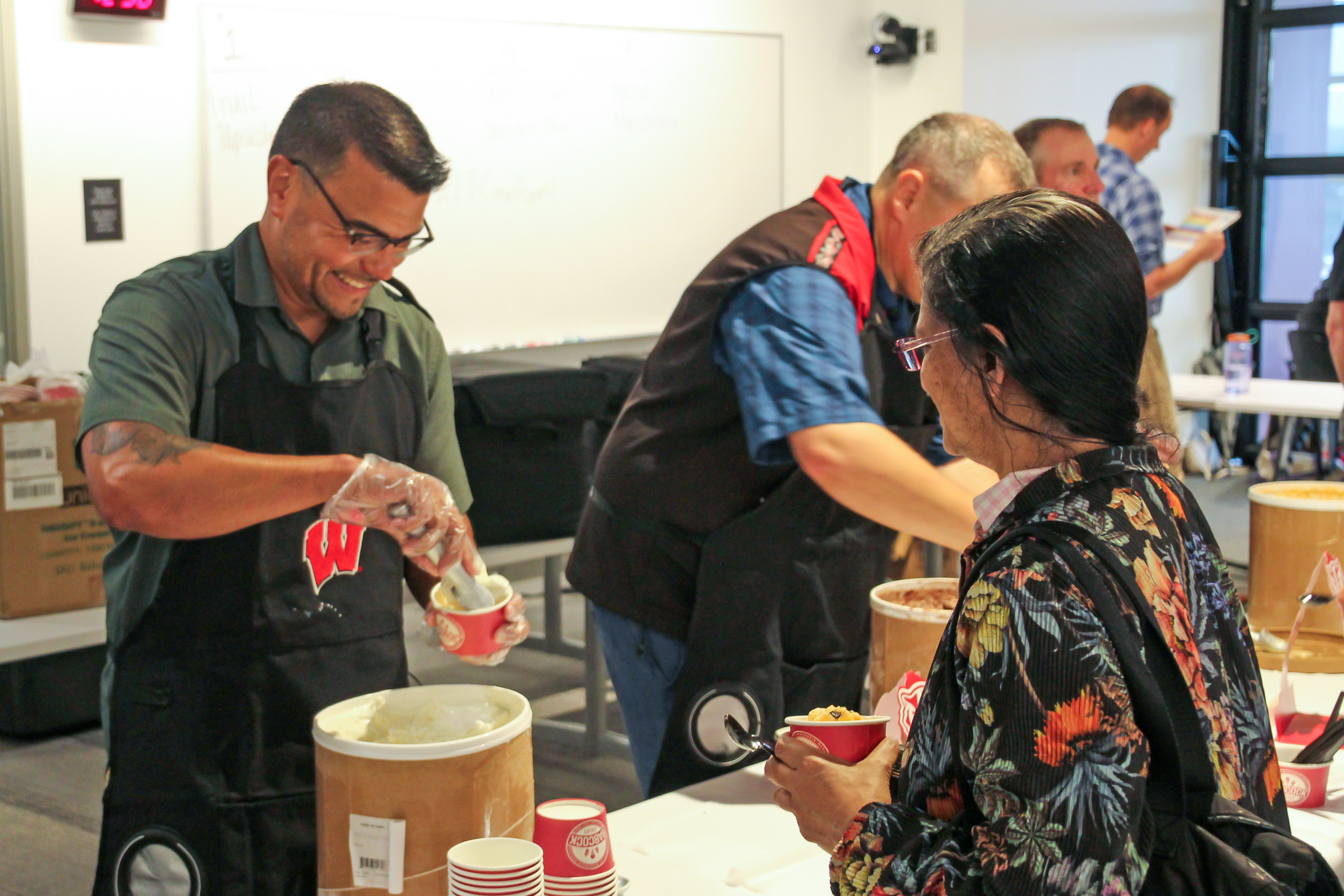 A man laughs while scooping ice cream 