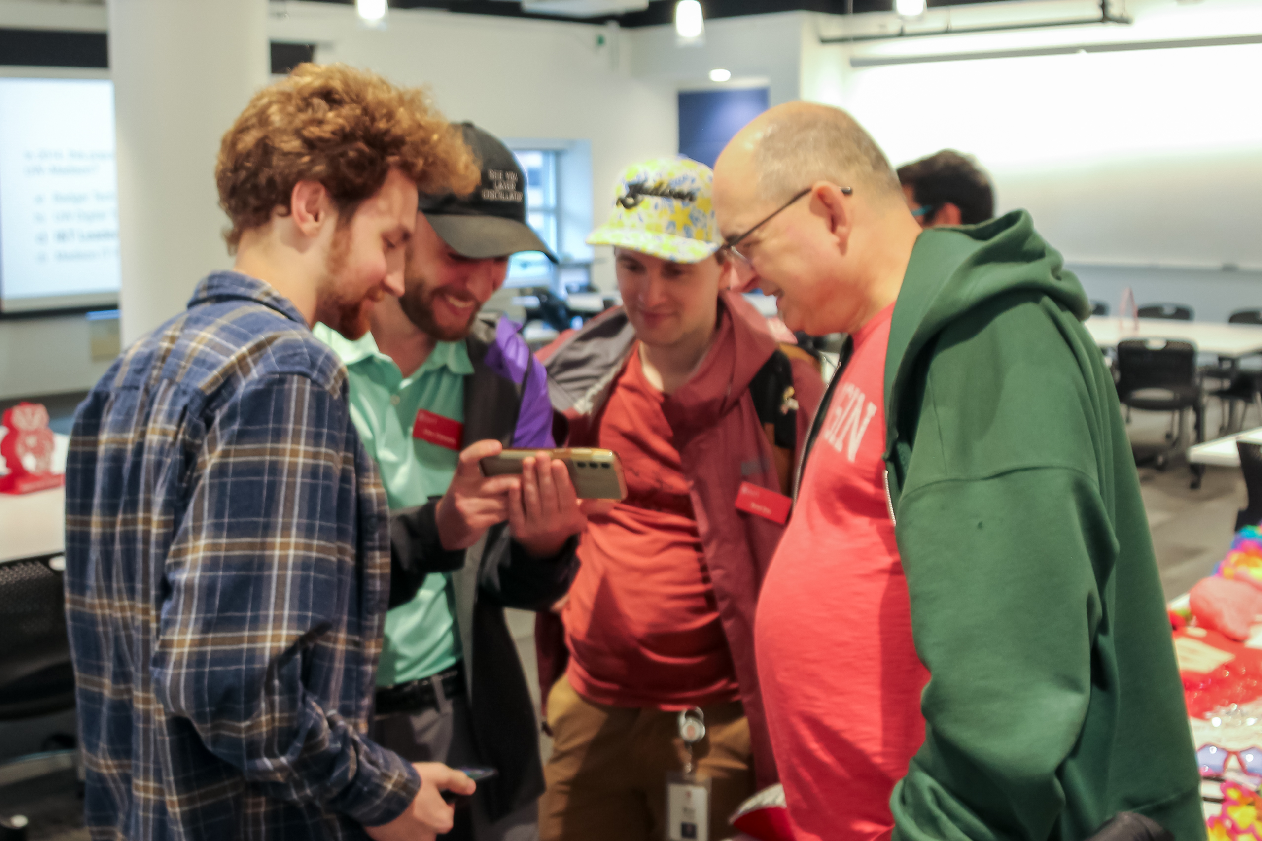 People crowd around a cell phone to watch a video