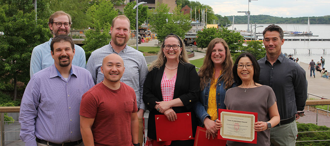 Eight people pose for a group photo outdoors