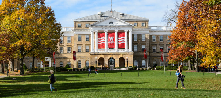 Bascom Hill in fall with students walking in the grass.