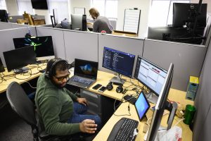 Help desk staff work at desks surrounded by tech devices.
